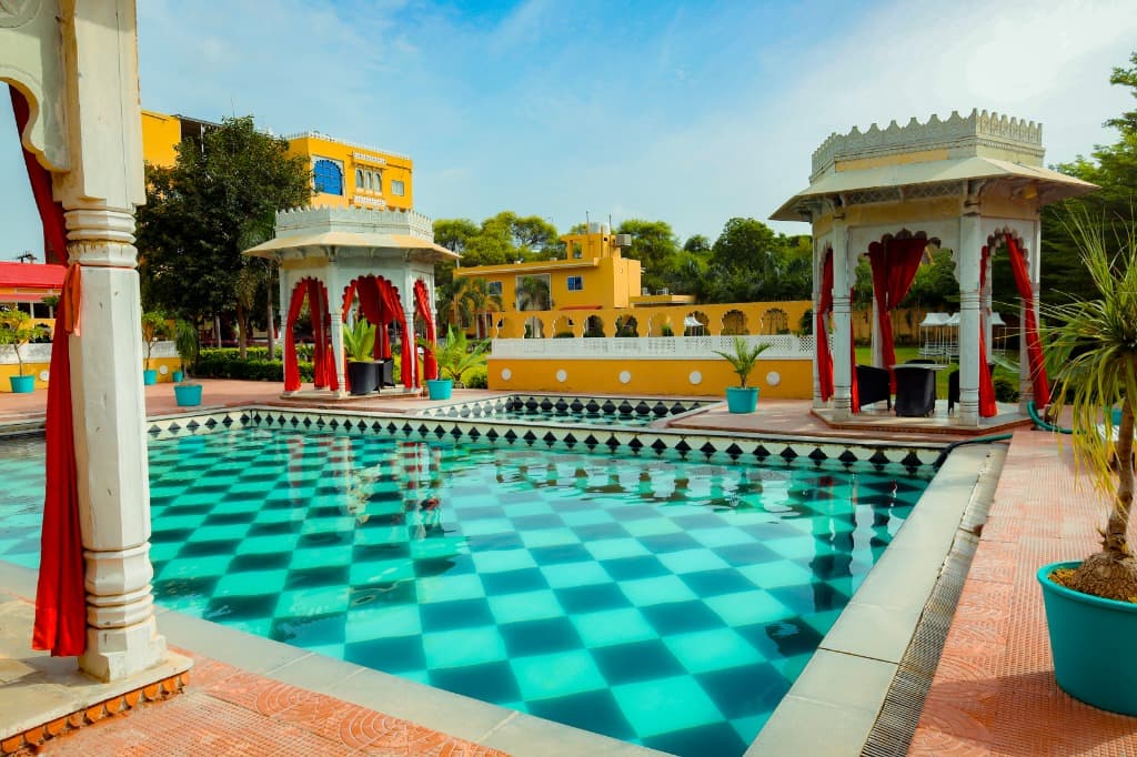 White marble gazebos with crimson drapes beside the pool