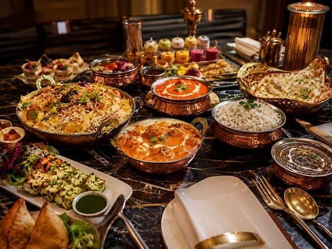 Royal copper handi feast table spread with biryani, Paneer Tikka, and tandoori naan